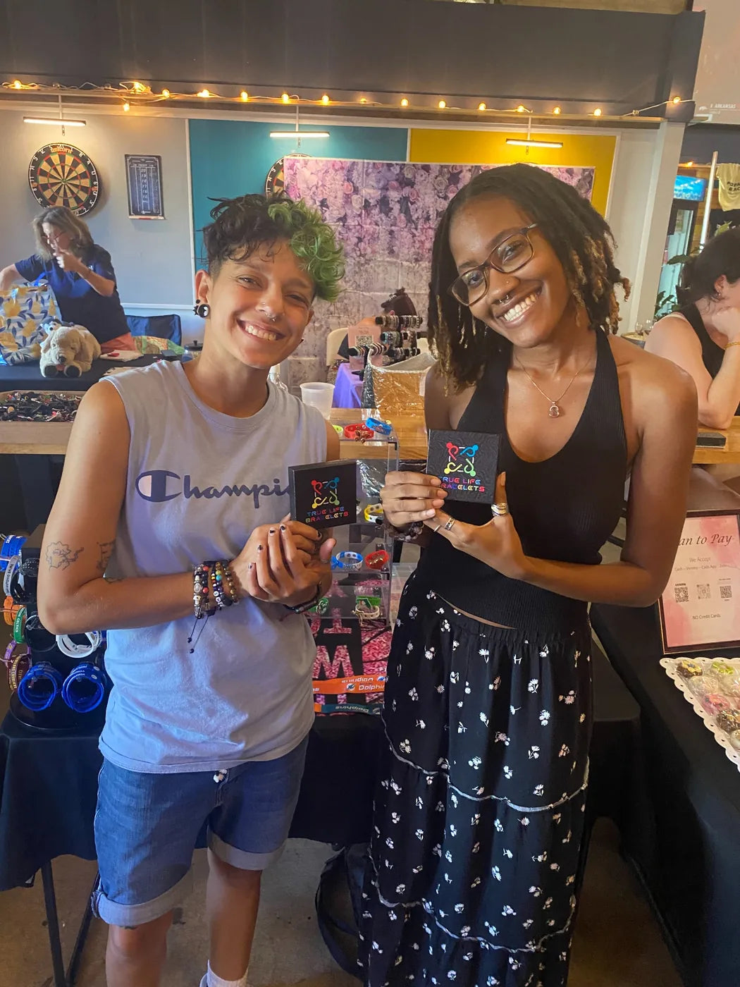 Two True Life Bracelets customers holding boxes at event booth